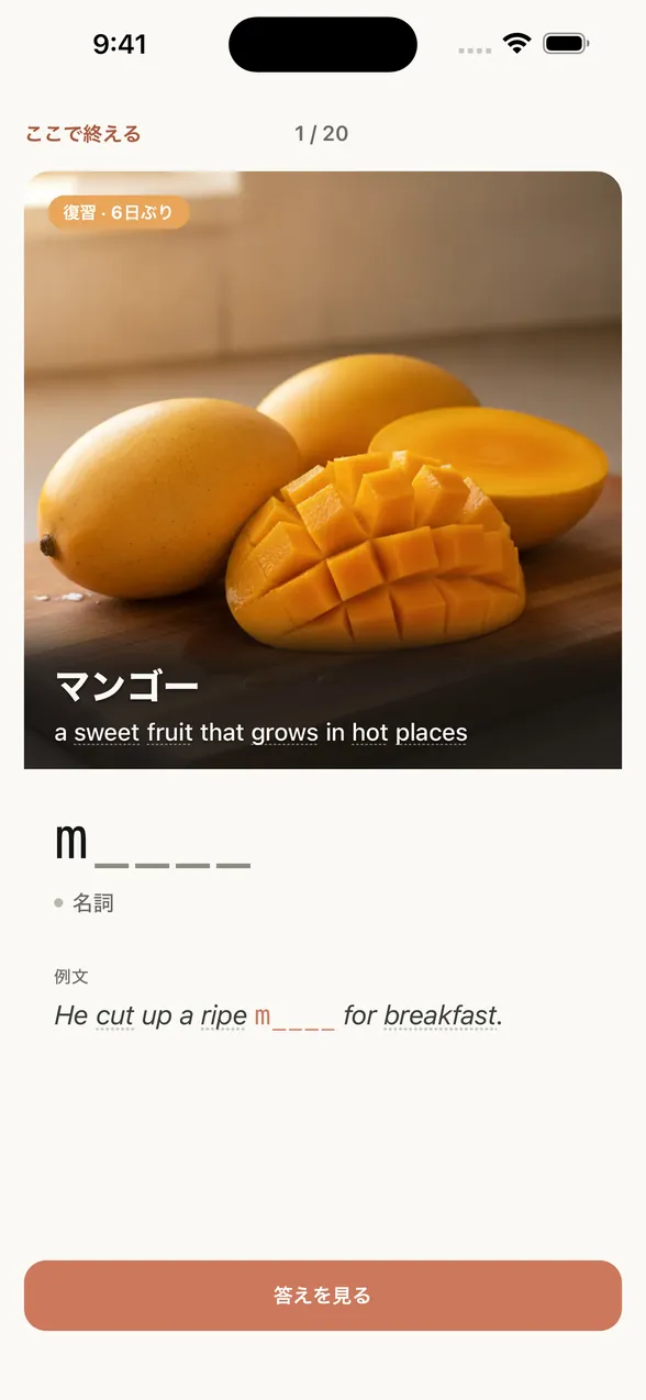 アプリの復習画面（答えを見る前）。画像に日本語の意味と英語の定義が重なり、その下に最初の1文字だけの文字ヒント。